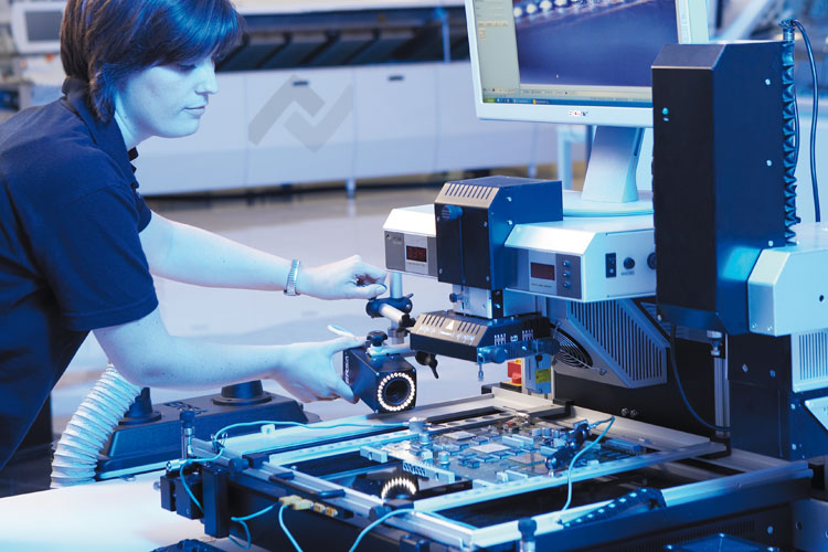 A technician adjusts equipment on a high-tech selective soldering assembly line, featuring a circuit board and monitors. The scene is lit with a cool blue tone, conveying precision.
