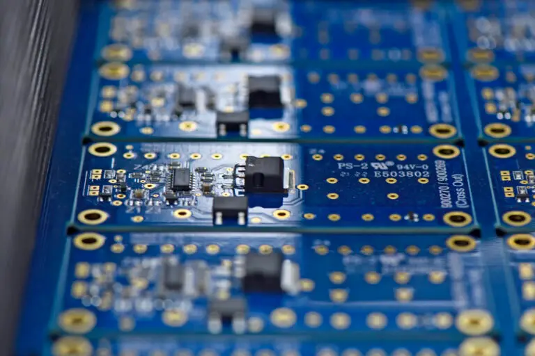 Close-up of several blue printed circuit boards aligned in rows, featuring small electronic components and gold-coloured connections. The tone is technical and precise.
