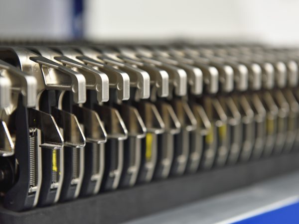 A close-up of a row of metallic, industrial I pulse machine parts arranged in parallel. The image conveys precision engineering and orderliness.