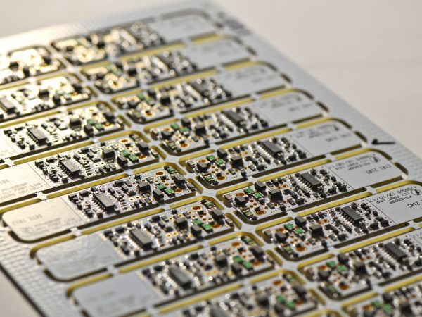 High throughput PCB assembly display, aligned in rows with visible circuits, resistors, and capacitors. The lighting highlights their metallic texture.