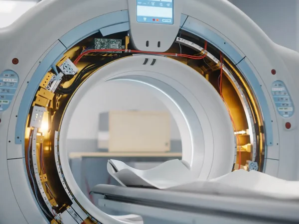 Close-up of an empty CT scanner in a hospital room, highlighting its circular structure and electronic components, conveying a clinical and sterile ambiance.